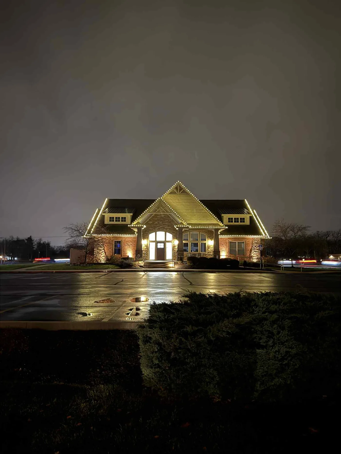 A large brick property in northeast Indiana lit up with installed white holiday lighting at night
