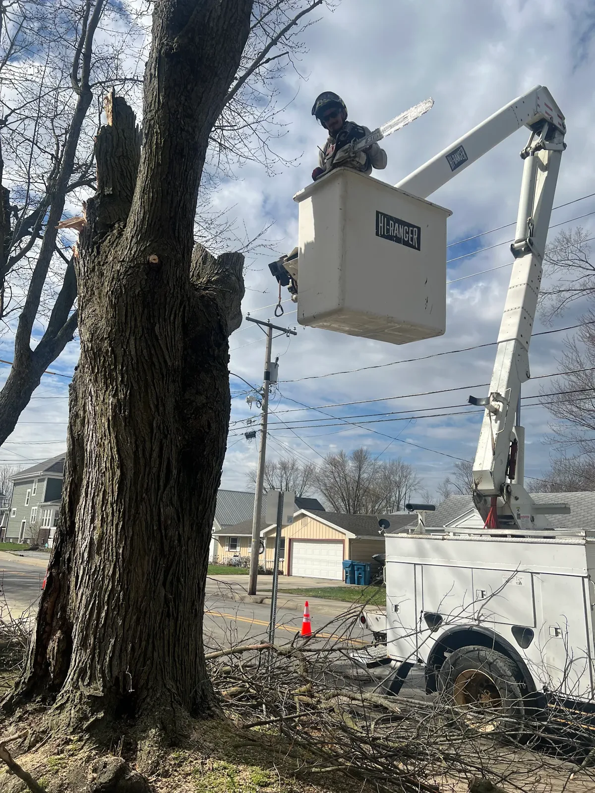 Klass bucket truck operator in a Hi-Ranger lift working a large tree in Fort Wayne